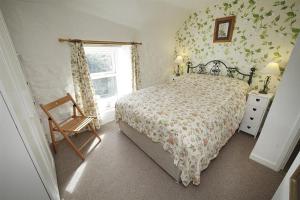 a bedroom with a bed and a chair and a window at 3 Bed in Swansea oc-hh405 in Llanmadoc
