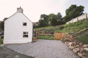 a small white house on a gravel road at 3 Bed in Swansea oc-hh405 in Llanmadoc