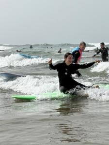 a group of people riding waves on surfboards in the ocean at Tayri Surf House Aourir in Agadir