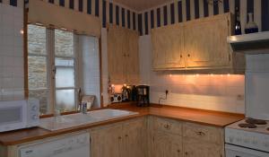 cocina con armarios de madera y fregadero blanco en Le Petit Maur en Spa