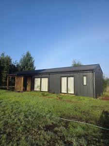 a black house on a field with a grass yard at Estancia del Sol in Putúe