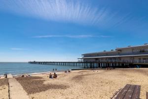 a beach with people sitting on the sand and a pier at 3 Bed in Felixstowe oc-p29748 in Felixstowe
