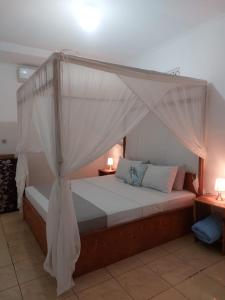 a bedroom with a canopy bed with two lamps at Tapada in Gili Islands