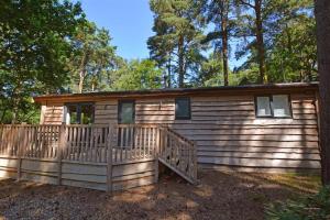 a log cabin in the woods with a large porch at 2 Bed in Weybourne oc-1628 in Kelling
