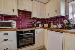 a kitchen with white cabinets and a red tiled wall at 2 Bed in Gayle oc-ds912 in Hawes