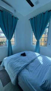 a blue bedroom with a bed with blue curtains at Paradise Homestay Marang in Marang +10 photos