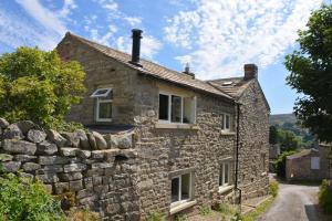 ein altes Steinhaus mit einer Steinmauer in der Unterkunft 2 Bed in High Fremington oc-ds375 in Reeth