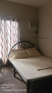 a bed in a bedroom next to a window at Little John's Town Inn in Coron