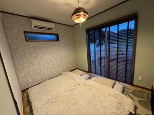 a bedroom with a bed and a large window at SerenityBlueAmami in Tatsugo