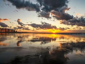 a sunset on the beach with the reflection in the water at Apartment with Pool and Sea View in Middelkerke +10 photos