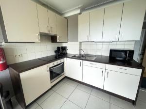 a kitchen with white cabinets and a black counter top at Apartment with Pool and Sea View in Middelkerke