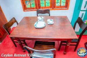 a wooden table with chairs and a table with a bowl at Ceylon Retreat Villa in Kamburugamuwa