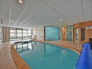 a large swimming pool with blue water in a building at Chalet in Odeigne with Private Pool & Sauna in Manhay