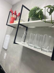 a shelf with glasses and potted plants on it at Seja Bem-Vindos, sinta-se em Casa ! in São Lourenço