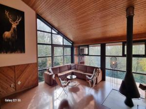 a living room with a couch and some windows at Chalet in Odeigne with Private Pool & Sauna in Manhay