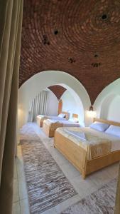 three beds in a room with a brick wall at Luxor Family Home in Naj‘ ar Rizqah
