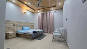 a bedroom with a bed and a chair in it at Aashvika Homes in Katrain