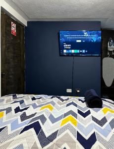 a bedroom with a bed with a tv on a wall at Hospedajes Alta Terra in Quetzaltenango