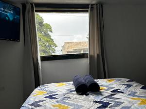 a bed with two blue towels on it with a window at Hospedajes Alta Terra in Quetzaltenango +10 photos