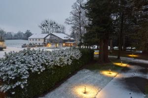 a house with lights in front of a hedge with flowers at Hôtel le Corbusson Laval Ouest in Saint-Berthevin-sur-Vicoin