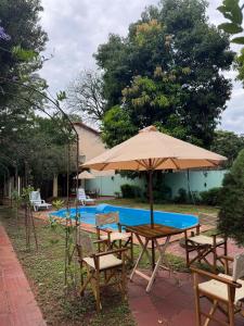 Ein Tisch und Stühle mit einem Sonnenschirm neben einem Pool in der Unterkunft Casa quinta en Capiatá in Capiatá
