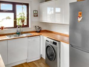 a kitchen with white cabinets and a washing machine at At Last in Rhiconich