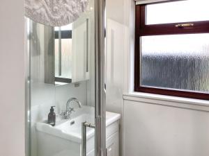 a white bathroom with a sink and a window at At Last in Rhiconich +4 photos