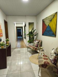 a living room with two chairs and a painting on the wall at Pousada Hangar- Seu familiar e aconchegante espaço em Belém in Belém