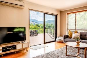 a living room with a large television and a balcony at Cindy's View in Bright