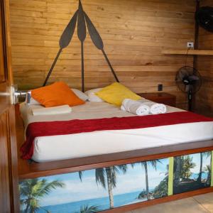 a bed with orange and yellow pillows in a room at Playa Terküa hotel in Nuquí