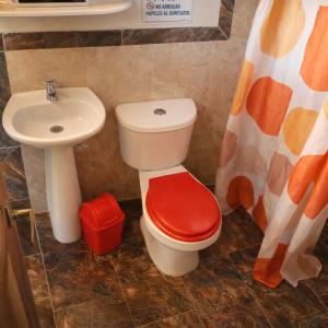 a bathroom with a sink and a toilet with a red seat at Playa Terküa hotel in Nuquí