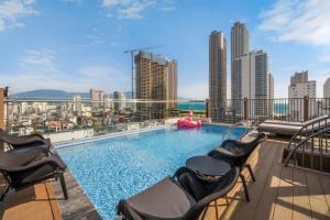 a pool on the roof of a building with chairs at Amber Bay Hotel & Suites Da Nang in Danang