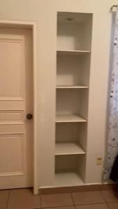 a closet with white shelves next to a door at Private room lcba in La Ceiba