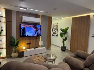 a living room with a couch and a tv at Luxury 2BR Pool View Apartment Hotel Style in New cairo