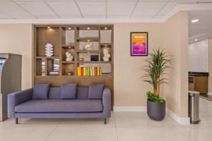 a blue couch in a waiting room with a plant at B&B Hotel Miami Airport in Miami
