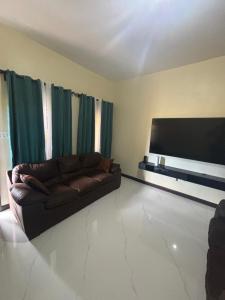 a living room with a couch and a flat screen tv at Serenity Palm Villa in Runaway Bay