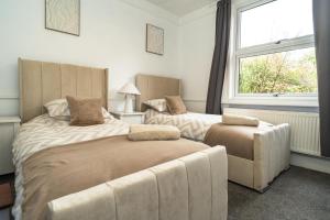 a bedroom with two beds and a chair and a window at Upper Grosvenor Suite in Royal Tunbridge Wells
