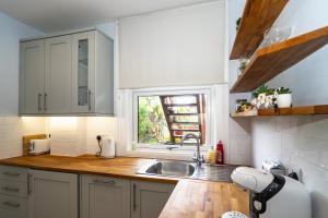 a kitchen with white cabinets and a sink and a window at Upper Grosvenor Suite in Royal Tunbridge Wells