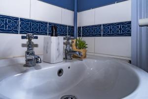 a white sink in a bathroom with blue tiles at Upper Grosvenor Suite in Royal Tunbridge Wells