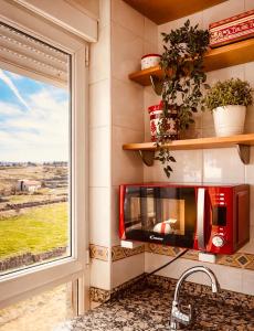 a kitchen with a red microwave and a window at El Rincón del Marqués in Las Navas del Marqués