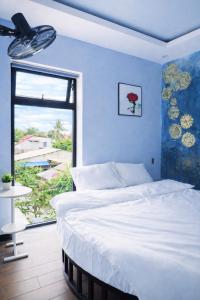 a bedroom with a white bed and a window at Victoria Hostel Huế in Hue