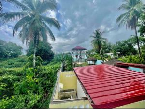 a view of a house with a red roof and palm trees at Lucenas B&B near Maravilla White Sand Beach in Maraat