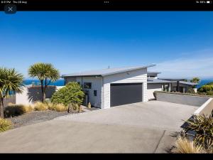 a white house with a garage and palm trees at Oceanview Haven B&B in Dunedin