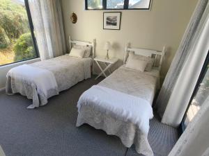 two beds in a room with a window at Oceanview Haven B&B in Dunedin