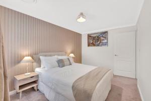 a bedroom with a large white bed and two lamps at Premium Large Cosy Home with Private Pool in Perth +15 photos