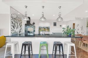 a kitchen with a counter with four stools at Premium Large Cosy Home with Private Pool in Perth
