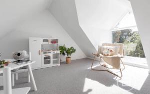 a white living room with a chair and a kitchen at Marthas Tree Top Sanctuary in Mount Martha