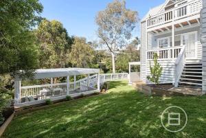 a white house with a white fence and a yard at Marthas Tree Top Sanctuary in Mount Martha