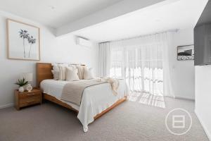 a white bedroom with a bed and a large window at Marthas Tree Top Sanctuary in Mount Martha