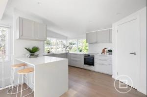 a white kitchen with white cabinets and a white island at Marthas Tree Top Sanctuary in Mount Martha